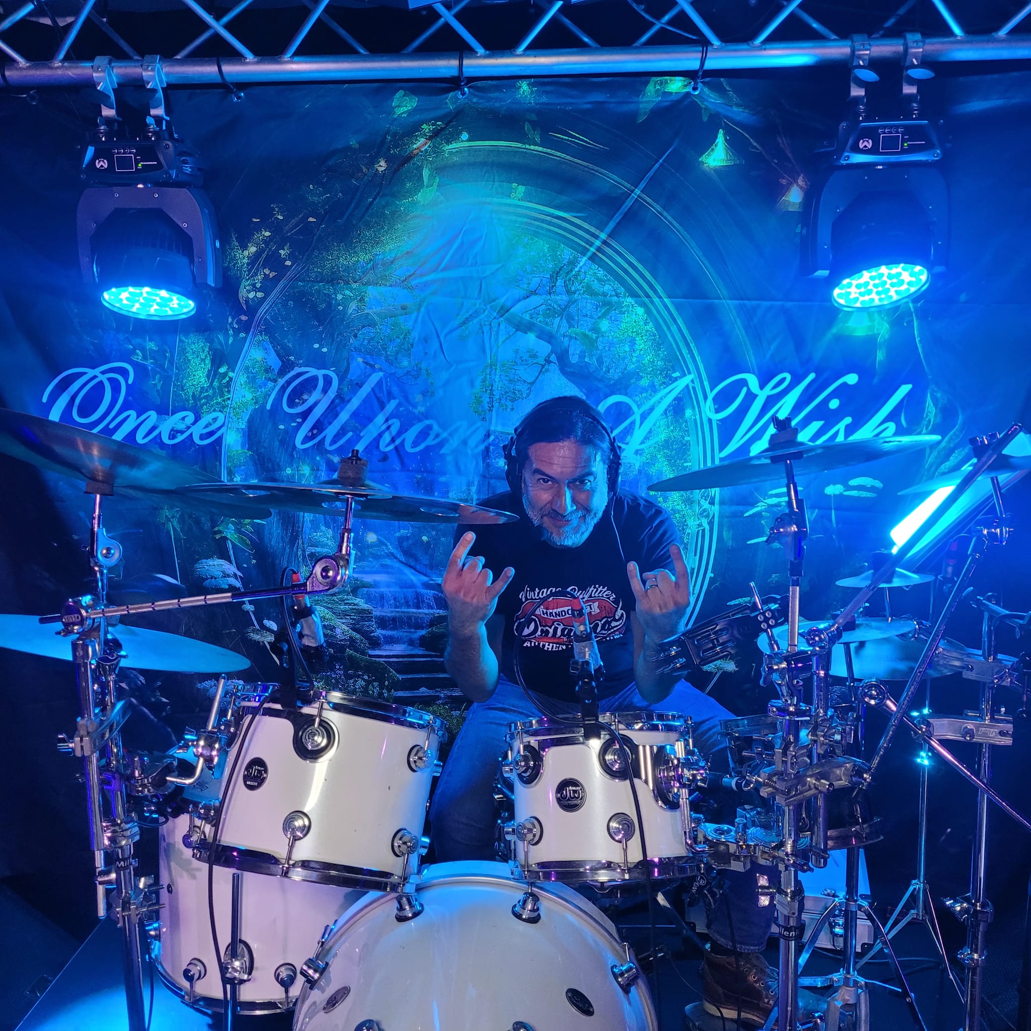 The image depicts a man sitting behind a drum set, with the text "Once Upon A Wish" written in white cursive font across t...